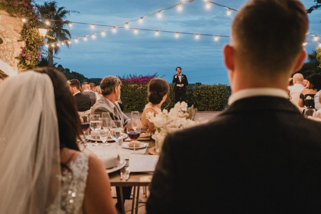 Bride and groom listening to a wedding speech during outdoor dinner at Almiral de la Font