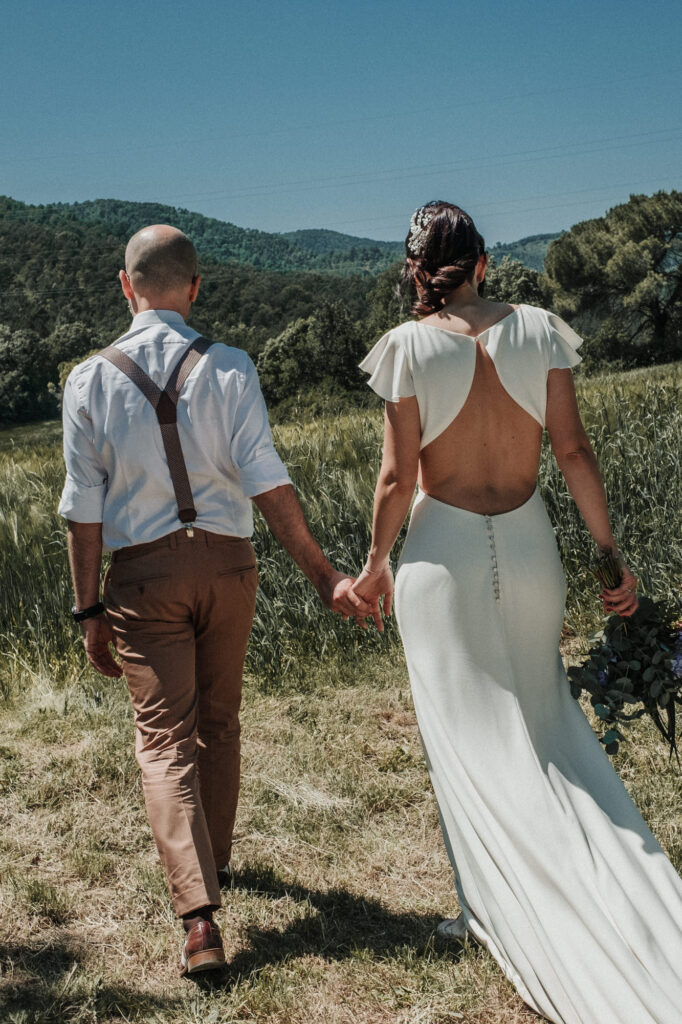 Bride and groom holding hands during their meadow session at El Dalmau