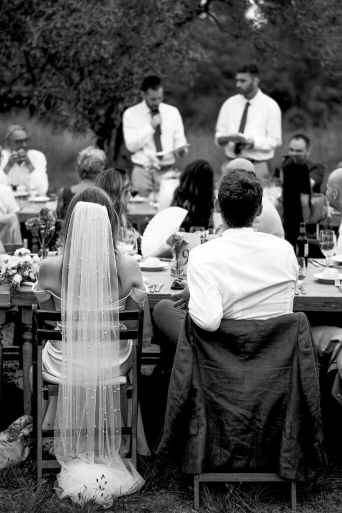 Bride and Groom liste to speeches during outdoor dinner at Mas Terrats
