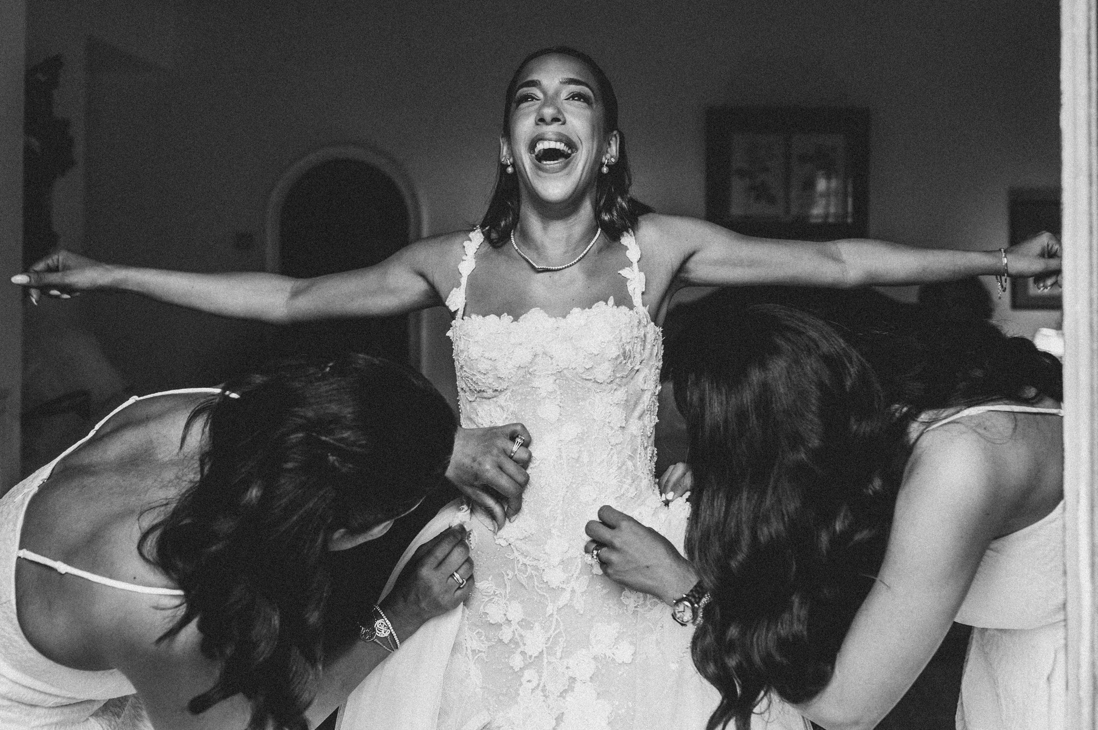 Bride getting in her dress by a window before the wedding