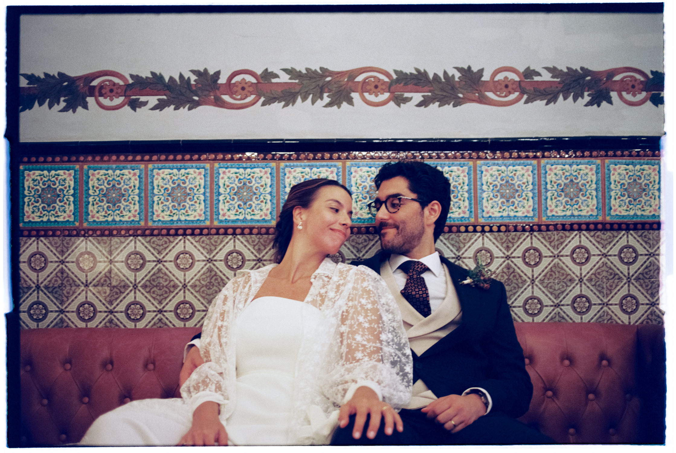 Bride and groom seated on a sofa looking each other