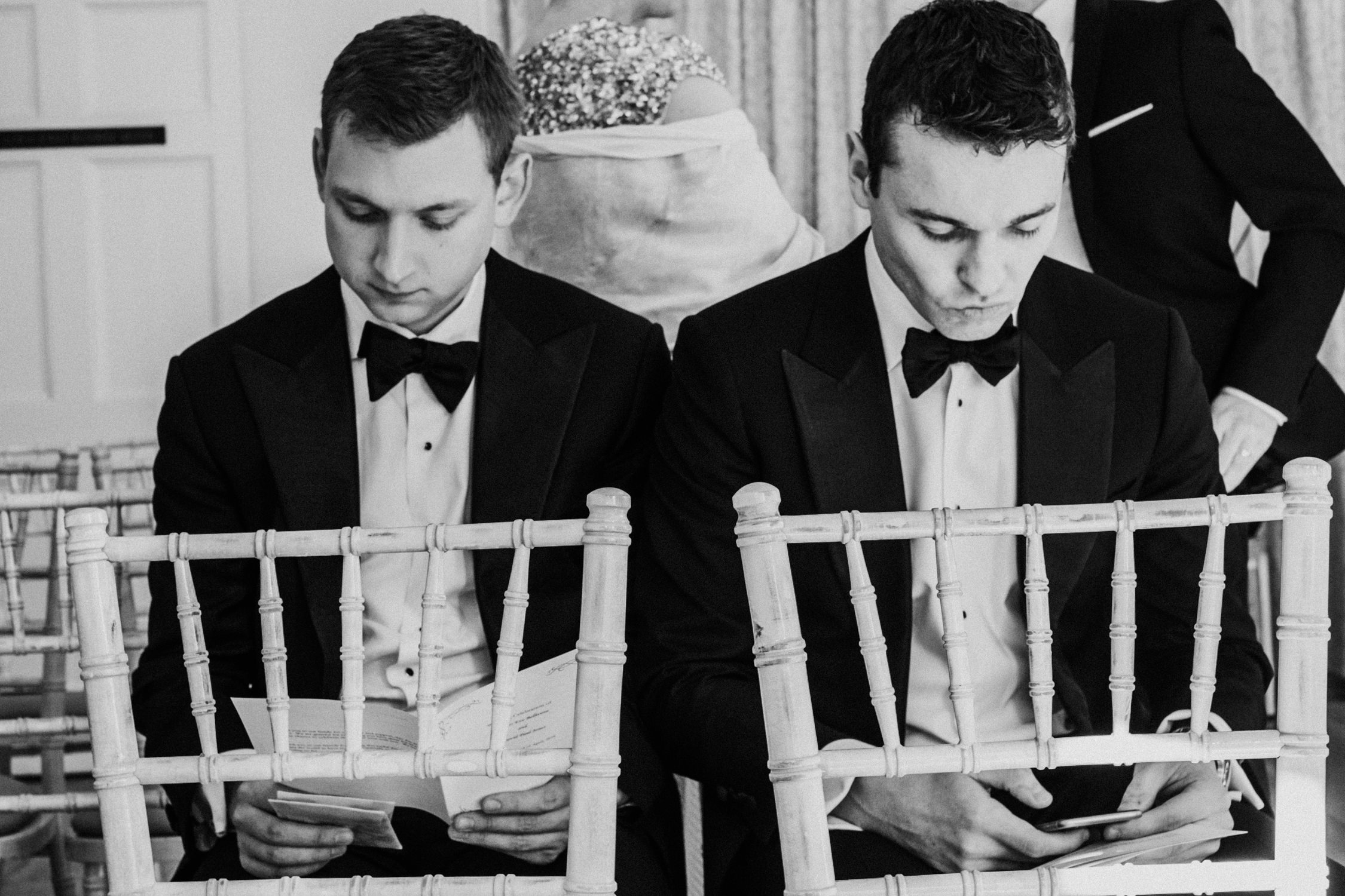 Best men seated before the ceremony in black tie rehearsing their reading